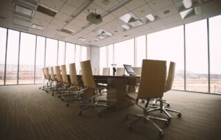 photo of a conference room with many large windows, a large table and 18 chairs around it shot from an angle