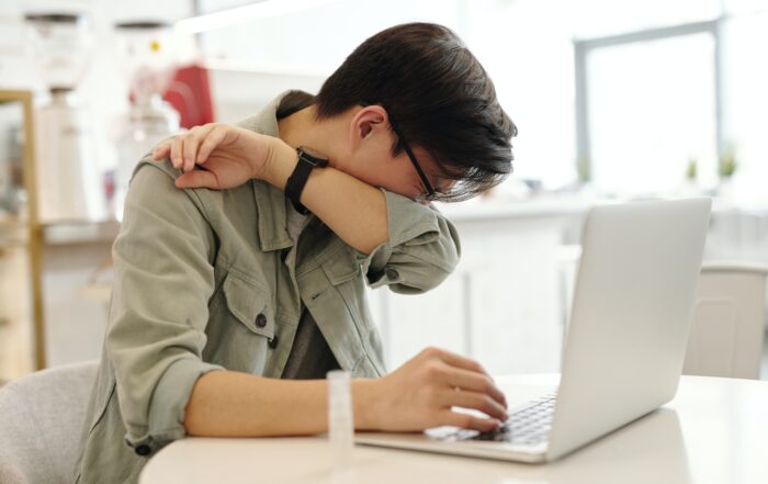 Man Sneezing while working at a computer in an office break area